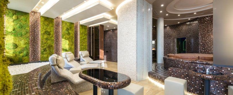 Comfortable chairs and bathtubs in spacious contemporary spa center with mosaic elements and walls decorated with fresh green plants